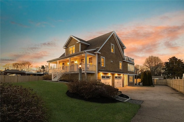 property exterior at dusk with fence, stairs, driveway, a garage, and a yard
