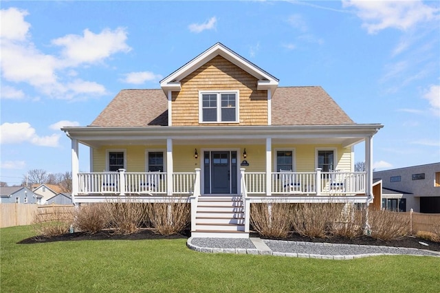 view of front facade with a front lawn, fence, a porch, and roof with shingles