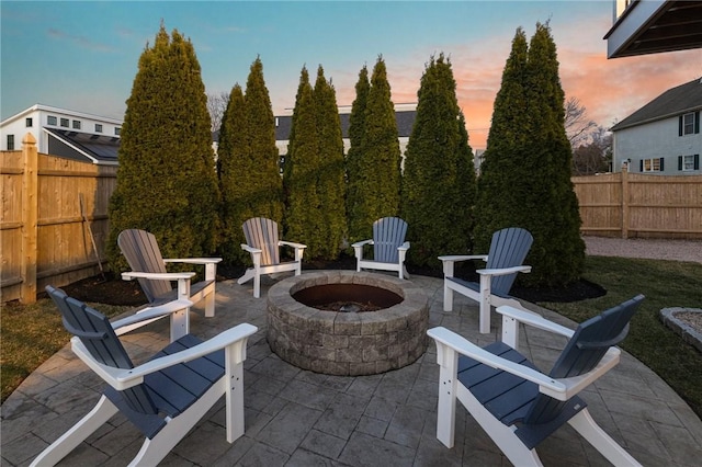 patio terrace at dusk featuring an outdoor fire pit and a fenced backyard