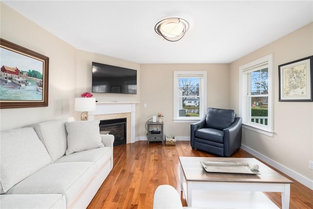 living area featuring baseboards, light wood-type flooring, and plenty of natural light