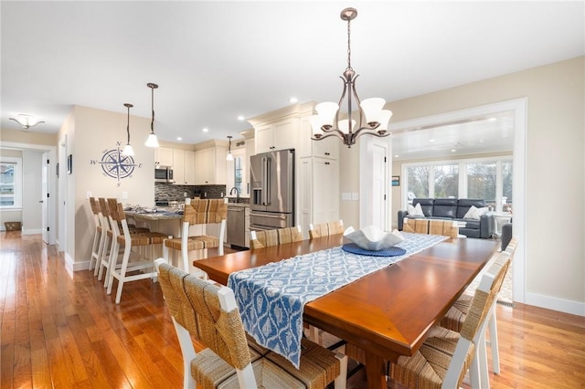 dining area featuring baseboards, recessed lighting, a notable chandelier, and light wood finished floors