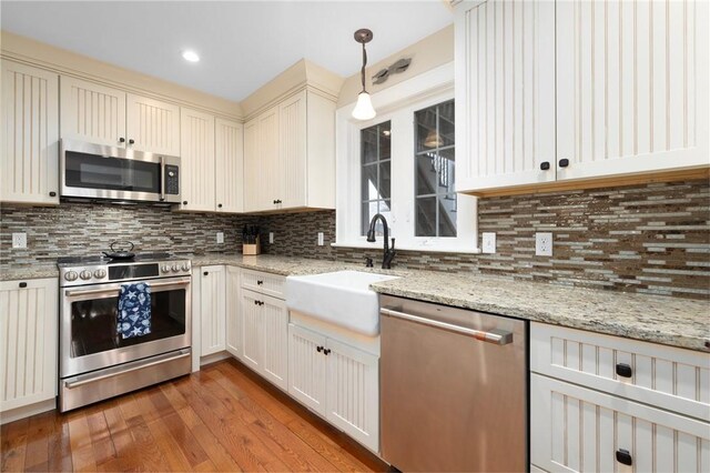 kitchen featuring backsplash, a sink, appliances with stainless steel finishes, and light wood finished floors