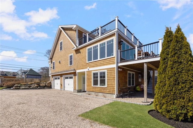 rear view of house featuring gravel driveway, a garage, and stairway
