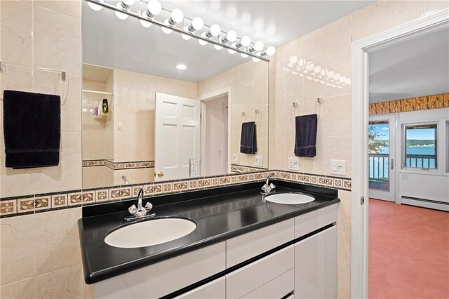 bathroom featuring a baseboard heating unit, double vanity, tile walls, and a sink