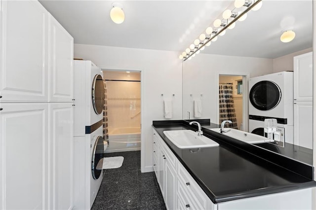 full bath featuring shower / bath combo with shower curtain, granite finish floor, stacked washing maching and dryer, and vanity