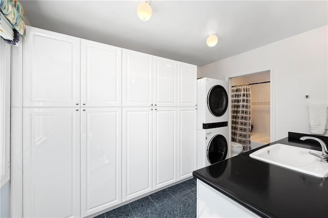 laundry room with stacked washing maching and dryer, a sink, and cabinet space