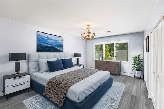 bedroom with visible vents, baseboards, an inviting chandelier, crown molding, and wood finished floors