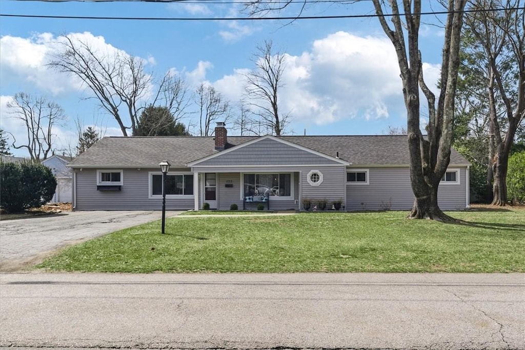 single story home featuring a front yard, driveway, and a chimney