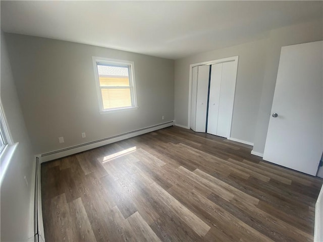 951 Main St, West Warwick, RI 02893 - unfurnished bedroom with a baseboard heating unit, dark wood-style flooring, and a closet