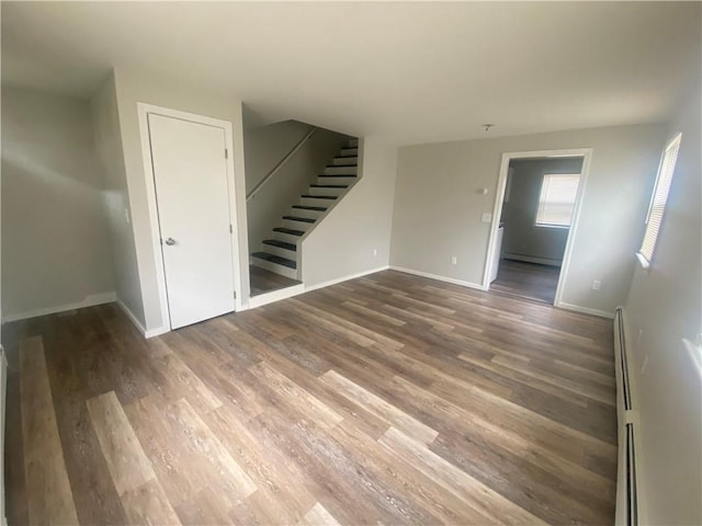 951 Main St, West Warwick, RI 02893 - empty room with stairway, wood finished floors, and a baseboard radiator