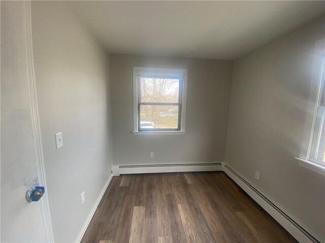 951 Main St, West Warwick, RI 02893 - empty room with a baseboard heating unit and dark wood-style floors