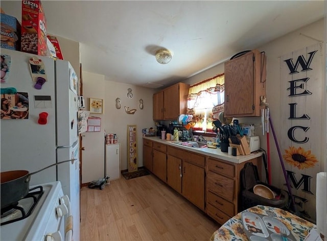 951 Main St, West Warwick, RI 02893 - kitchen with white appliances, light countertops, brown cabinets, and light wood finished floors