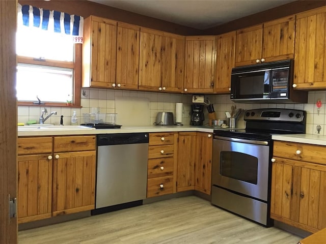 kitchen featuring light countertops, a sink, brown cabinetry, and appliances with stainless steel finishes