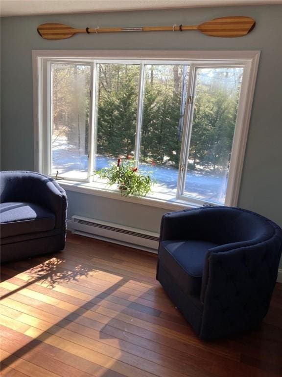 living area with wood-type flooring, plenty of natural light, and baseboard heating