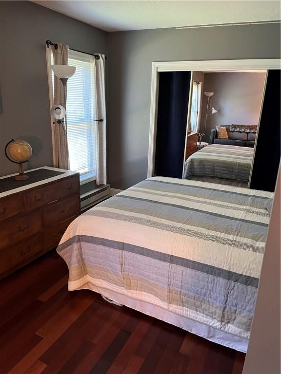 bedroom with dark wood-type flooring and baseboard heating