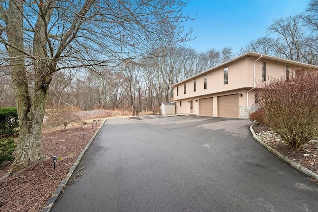 view of side of home featuring a garage and aphalt driveway