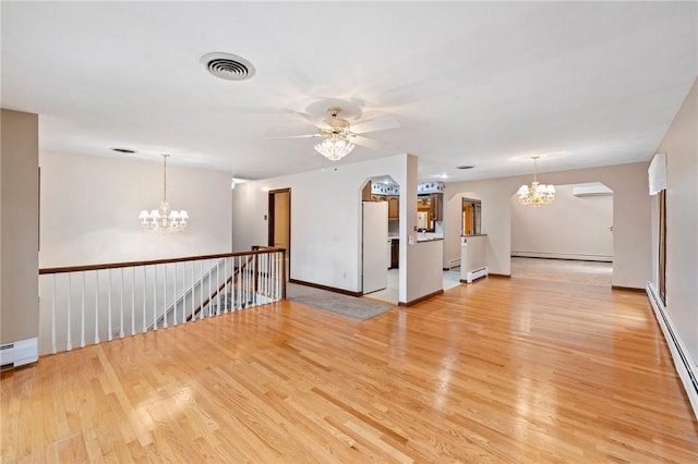 unfurnished room featuring visible vents, light wood-type flooring, ceiling fan with notable chandelier, a baseboard heating unit, and a wall unit AC