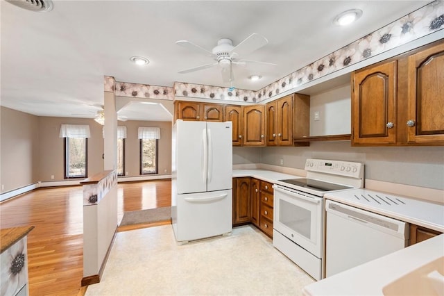 kitchen with brown cabinetry, white appliances, a baseboard radiator, and a ceiling fan