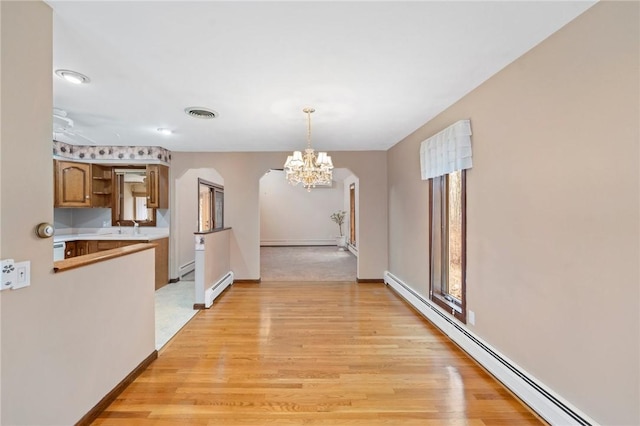 corridor with light wood-style flooring, a notable chandelier, a baseboard heating unit, and baseboard heating