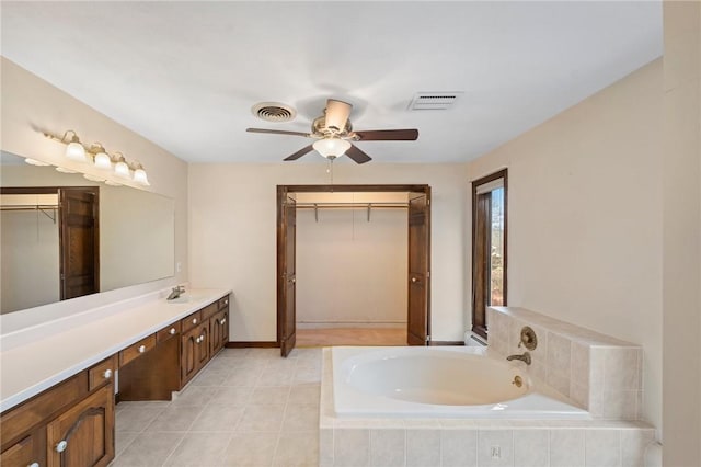 bathroom with visible vents, ceiling fan, a walk in closet, and a garden tub