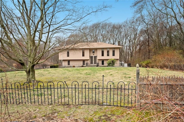 raised ranch with stucco siding, fence, and a front lawn
