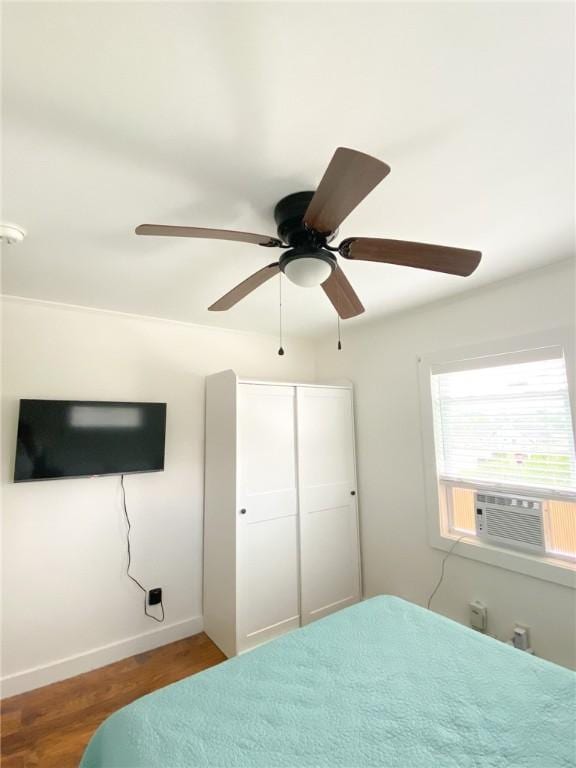 bedroom featuring baseboards, ceiling fan, cooling unit, and wood finished floors