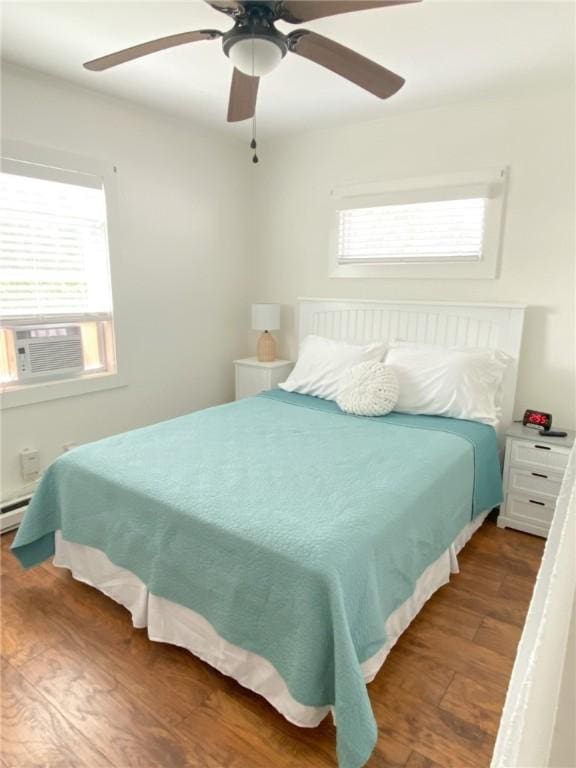 bedroom with a baseboard radiator, cooling unit, wood finished floors, and a ceiling fan