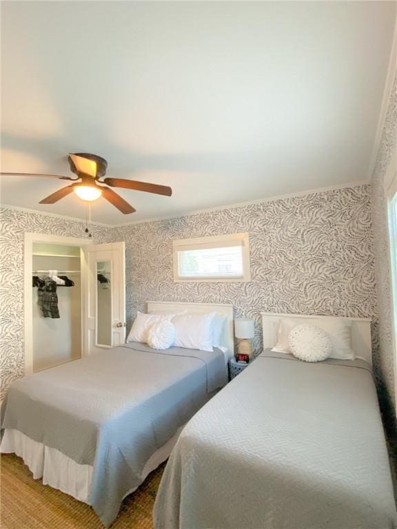 bedroom with wallpapered walls, ornamental molding, and a ceiling fan