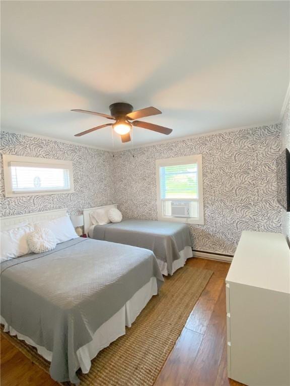 bedroom with wallpapered walls, multiple windows, and wood finished floors