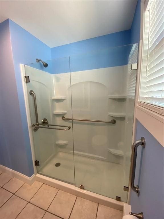 bathroom with tile patterned floors, baseboards, and a shower stall