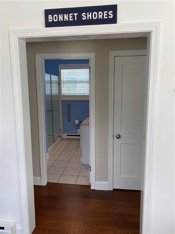 hallway with baseboards, light wood-style floors, and baseboard heating