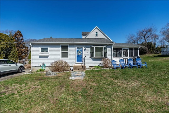 view of front facade with entry steps, a sunroom, and a front yard