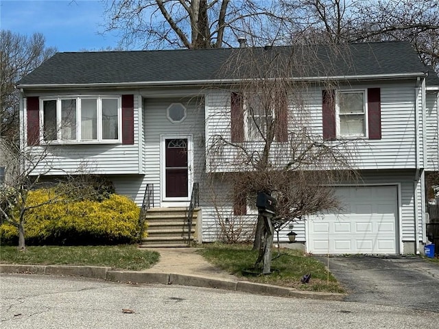 bi-level home with an attached garage, driveway, and entry steps