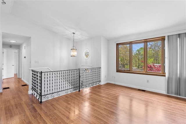spare room featuring baseboards, wood finished floors, and visible vents