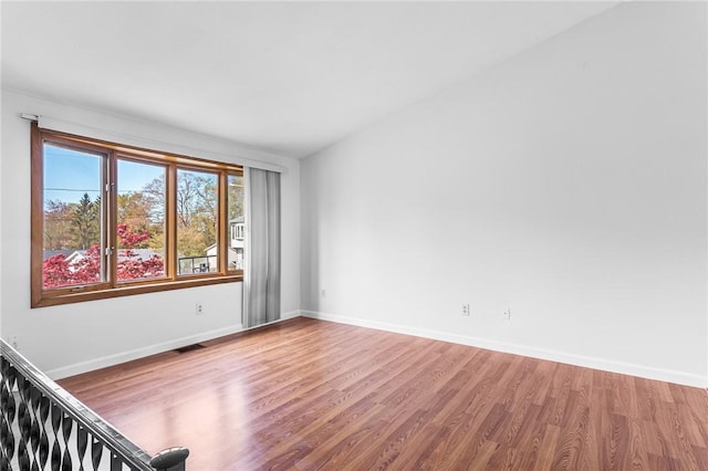 unfurnished room featuring baseboards, wood finished floors, and visible vents