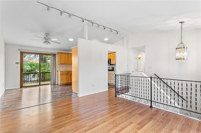 unfurnished living room featuring baseboards, ceiling fan with notable chandelier, light wood finished floors, and lofted ceiling