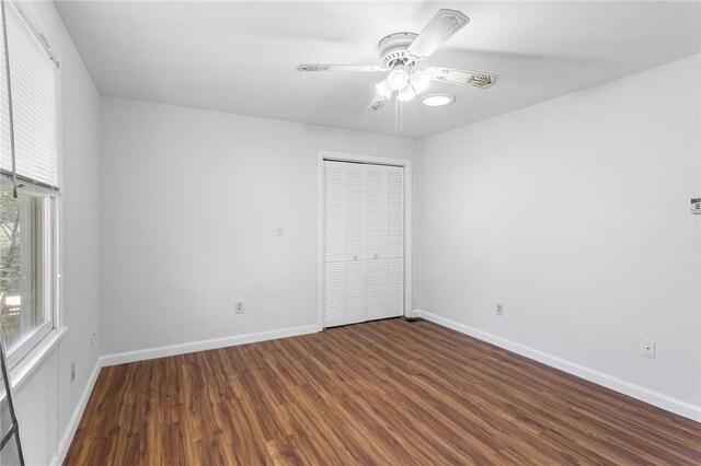 unfurnished bedroom featuring baseboards, ceiling fan, wood finished floors, and a closet