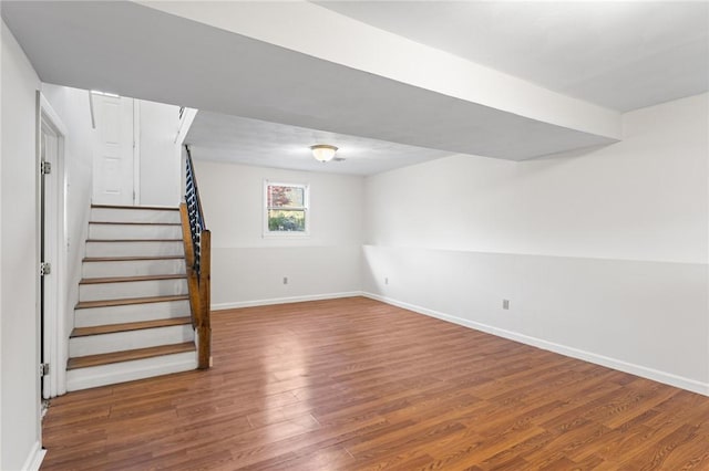 below grade area featuring baseboards, wood finished floors, and stairway
