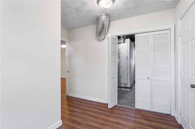 unfurnished bedroom featuring baseboards, wood finished floors, and a closet