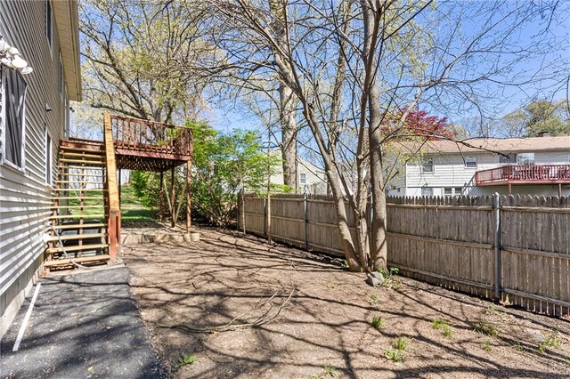 view of yard with a patio, a deck, fence, and stairs