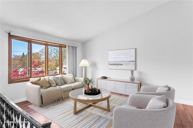 living area featuring baseboards, lofted ceiling, and wood finished floors