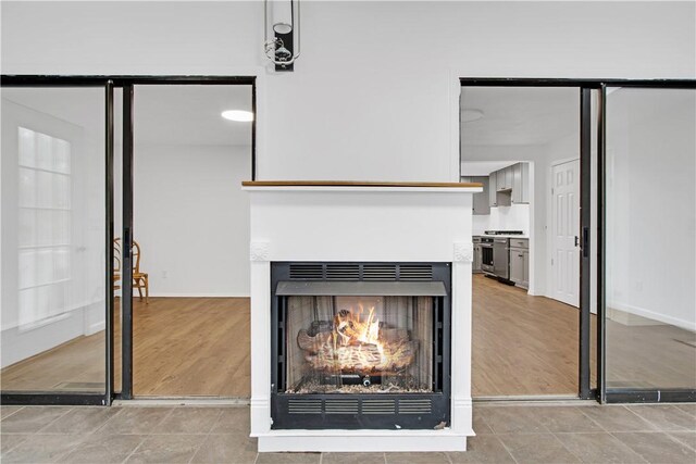20 Holly Hill Ct, East Greenwich, RI 02818 - room details with a warm lit fireplace, stainless steel range with gas stovetop, and wood finished floors