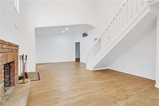 20 Holly Hill Ct, East Greenwich, RI 02818 - unfurnished living room with light wood-style floors, a fireplace, stairway, and a towering ceiling