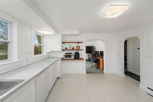 1737 Wampanoag Trl, Barrington, RI 02806 - kitchen with white dishwasher, open shelves, a desk, white cabinets, and arched walkways