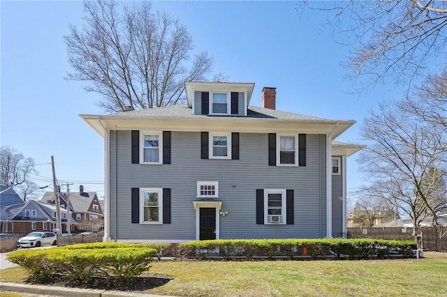 traditional style home with a chimney, fence, and a front yard