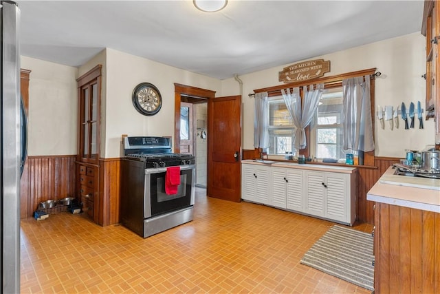 kitchen featuring light countertops, stainless steel appliances, brick patterned floor, and wainscoting
