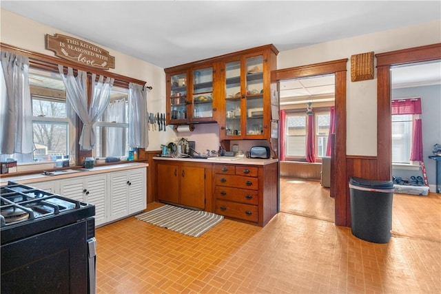 kitchen with light countertops, wainscoting, a wealth of natural light, and range with gas cooktop