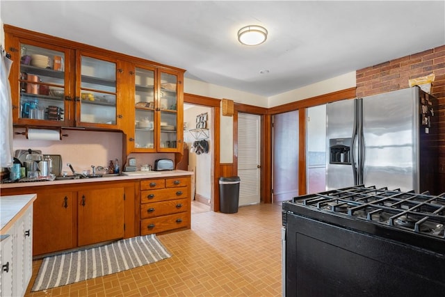 kitchen with black range with gas cooktop, glass insert cabinets, stainless steel fridge with ice dispenser, and light countertops