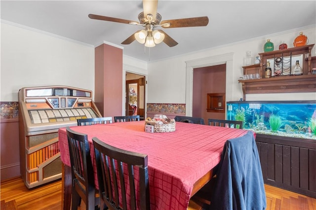 dining space featuring wood finished floors, a ceiling fan, and ornamental molding