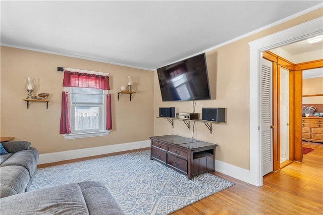 living room with wood finished floors, ornamental molding, and baseboards